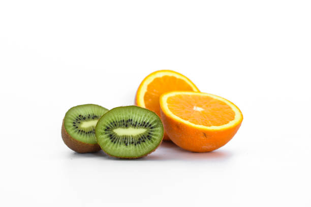 Selective focus. Sliced kiwi laid out on slices of orange and lemon. Ripe fruits stacked together, top view. Ingredients for fruit salad and fresh juic