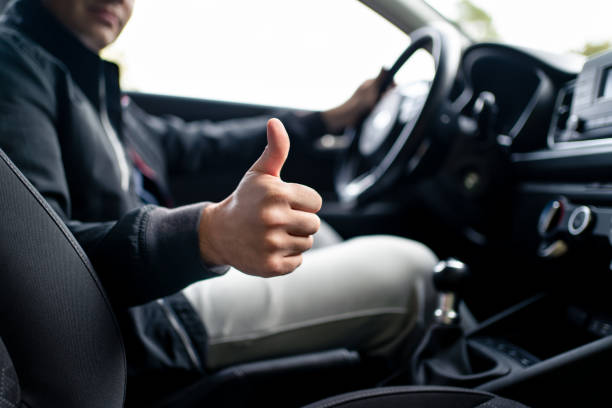 Happy driver in car, thumbs up. Man driving. Smiling positive new vehicle buyer and owner. Good customer service in taxi, dealership, insurance, inspection or maintenance business. stock photo