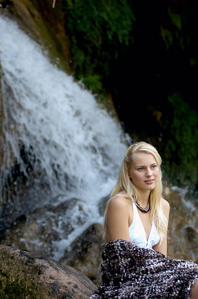 istock Young woman sitting by waterfall, wrapped in blanket 147786332