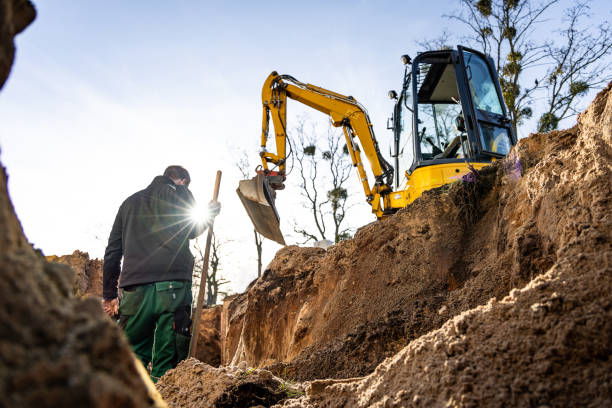 Excavation and earthwork at a construction site with a person and excavator Excavation and earthwork in progress at a construction site, featuring an operator and excavator machinery. Shot from inside the hole in the ground. bagger stock pictures, royalty-free photos & images