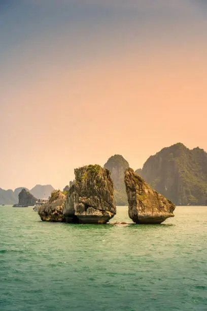 View of Hon Ga Choi Island or Cock and Hen, Fighting Cocks Island located in Ha Long bay, Vietnam, Trong Mai island, junk boat cruise and boats, popular landmark, famous destination Vietnam.