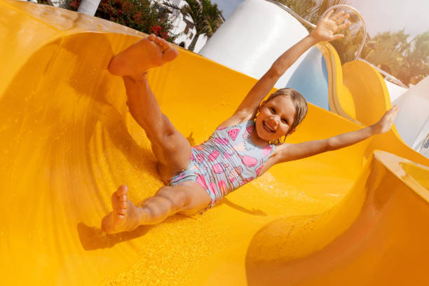happy child having fun on slide at outdoor water park. summer vacation stock photo