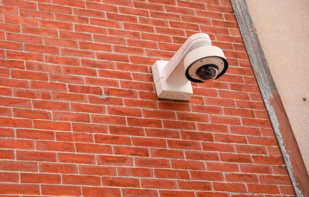 istock Security camera mounted on a building overlooking a busy street, while roadside camera on a pole captures passing vehicles on the highway 1477868059