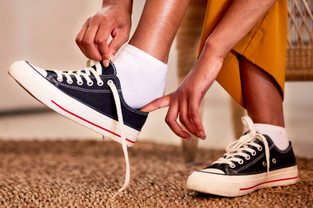 hands, shoes and lace getting ready for walk, travel or shopping on the carpet floor or mat at home. hand of person tying laces, fitting or putting on shoe in preparation for walking, journey or trip - shoe women fashion shoe store imagens e fotografias de stock