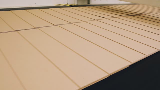 Cut cardboard moves along the conveyor at the packaging factory. Corrugated cardboard factory.
