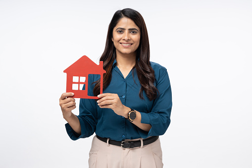 Portrait of happy businesswoman holding house on white background