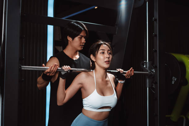 istock Woman working out Bodybuilder with coaching assistance to support weights at the gym. bodybuilder doing exercises with barbell. training sport healthy lifestyle bodybuilding. 1477871815