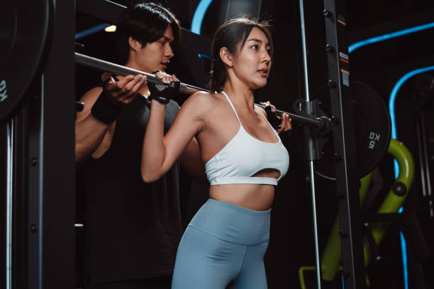 istock Woman working out Bodybuilder with coaching assistance to support weights at the gym. bodybuilder doing exercises with barbell. training sport healthy lifestyle bodybuilding. 1477871836