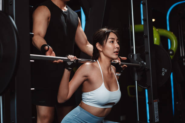 istock Woman working out Bodybuilder with coaching assistance to support weights at the gym. bodybuilder doing exercises with barbell. training sport healthy lifestyle bodybuilding. 1477871886