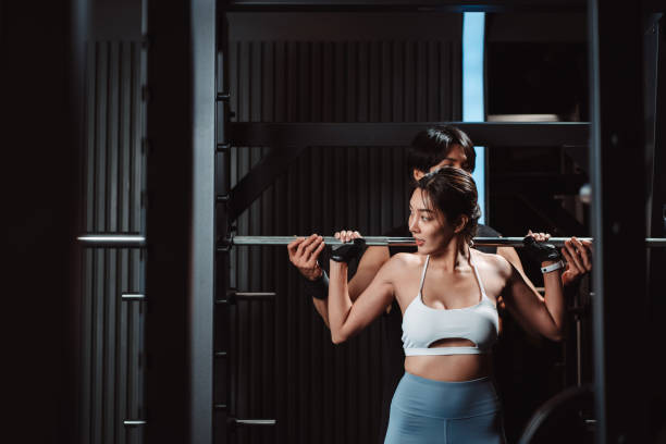 istock Woman working out Bodybuilder with coaching assistance to support weights at the gym. bodybuilder doing exercises with barbell. training sport healthy lifestyle bodybuilding. 1477873567