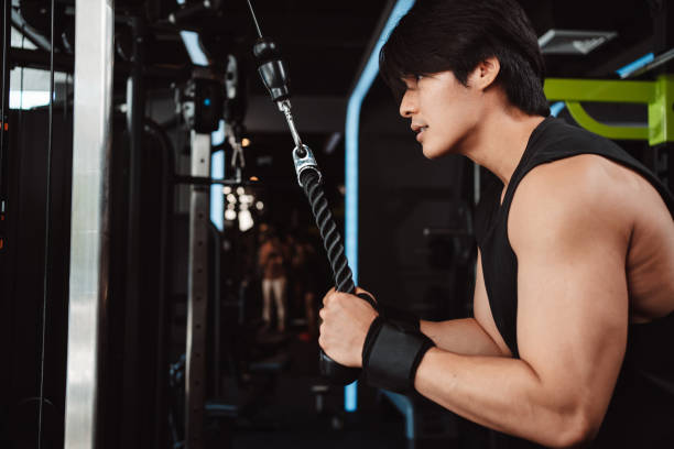 istock Man working out with weights training machine exercise lifting dumbbells at fitness gym. Fitness muscular body weight loss. Bodybuilding healthy lifestyle. 1477873582