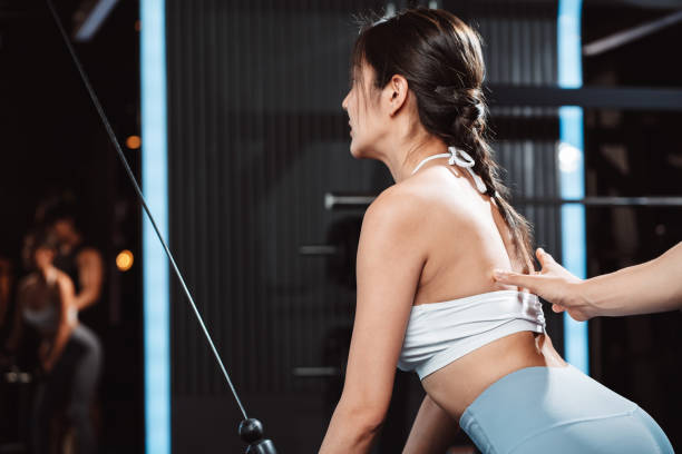 istock Woman working out Bodybuilder with coaching assistance to support weights at the gym. bodybuilder doing exercises with Machine. training sport healthy lifestyle bodybuilding. 1477873665