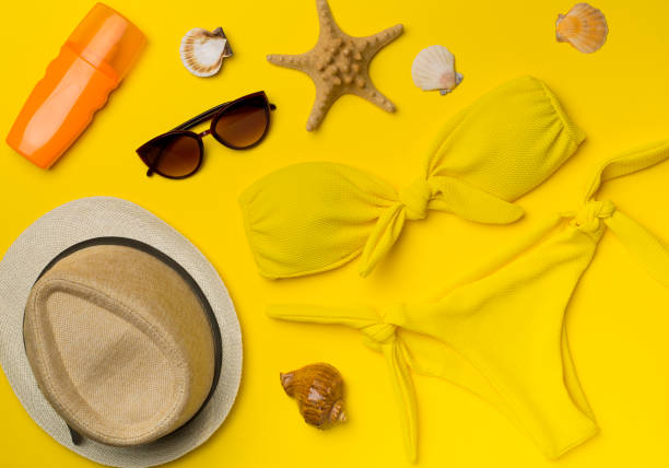 istock Beautiful yellow bikini and accessories on color background, top view 1477875609