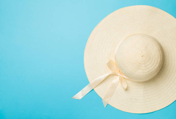 istock Beautiful straw hat with ribbon and bow on color background, top view 1477875626