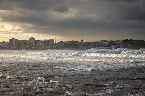 Exposure from the Gijon boardwalk of the beautiful seafront with great waves for surfing at Sunset, Spain.