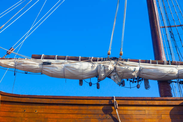 istock An old wooden caravel ship with folded sails against a blue sky with white clouds. 1477880585