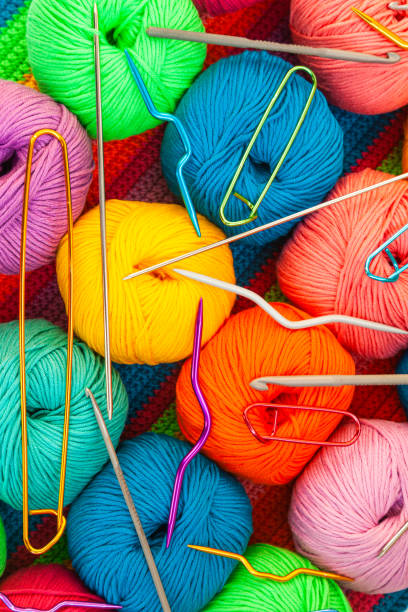 istock All for hand knitting. Knitted multi-colored handmade fabric with balls of multi-colored threads, pins and various knitting needles on it. 1477880654