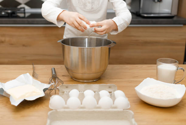 얼굴이 갈라지지 않고, 계란을 때리고, 현대적인 주방에서 반죽을 준비하고 섞지 않는 아이의 손 - eggs bowl cracked dining table 뉴스 사진 이미지