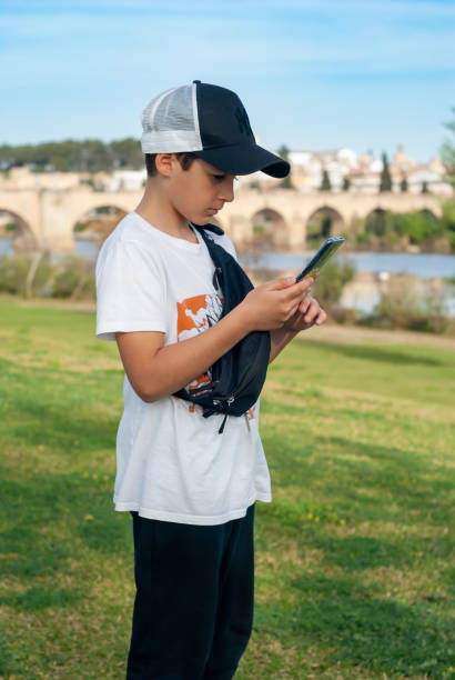 istock Boy with cap, using his smart phone in the park. 1477886608