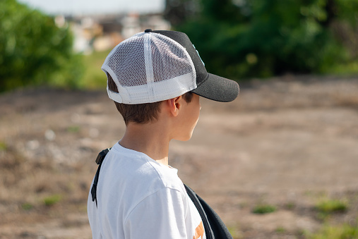 Image of boy in baseball cap, shot from the side.