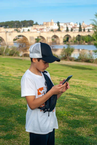 istock Boy with cap, using his smart phone in the park. Image taken from top to bottom. 1477886622