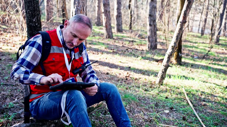 An environmental surveyor man checks the state of the forest with a digital tablet in hand