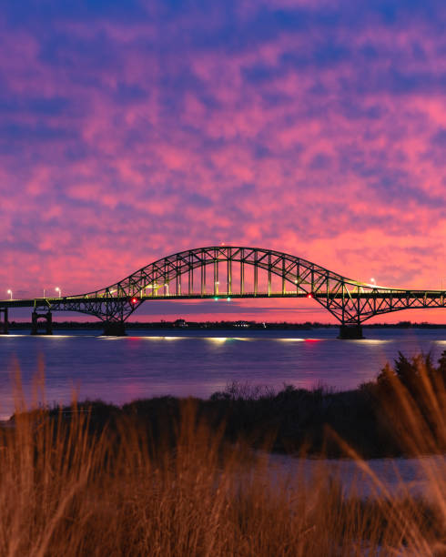 長い鋼鉄で結ばれたアーチ橋の後ろに鮮やかなカラフルな夕日空。ファイアーアイランドニューヨーク - cirrocumulus ストックフォトと画像