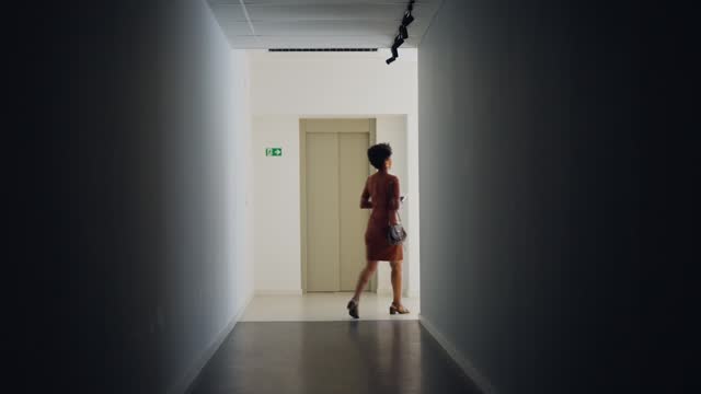 Silhouetted businesswoman walking along a corridor another hallway