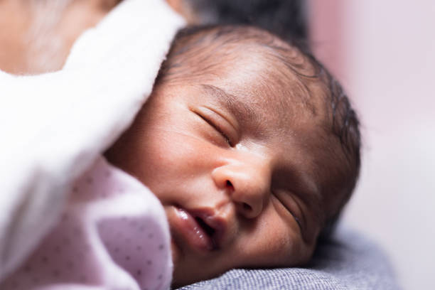 istock Cute little newborn baby curled up sleeping on shoulder with a white blanket 1477892989