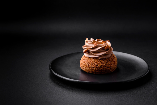 Delicious sweet shu cake with cream and nuts on a dark concrete background