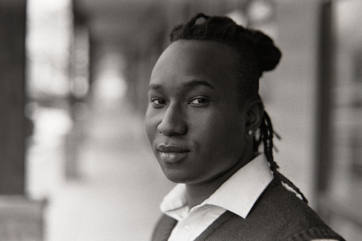 A 35mm black and white film scan of a young black man in a city.