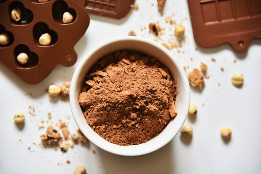 Cocoa powder, nuts and cookie crumbs, silicone molds for making chocolate, flat lay food sweetness.
