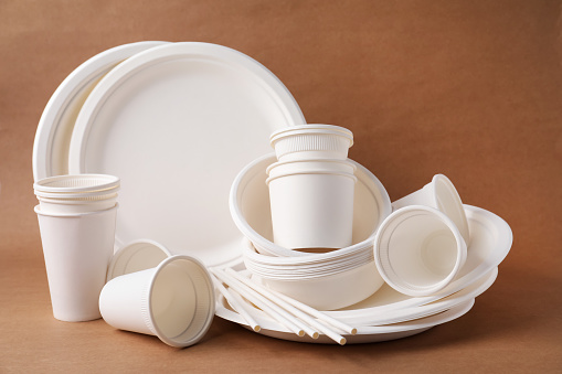 Set of disposable tableware on brown background