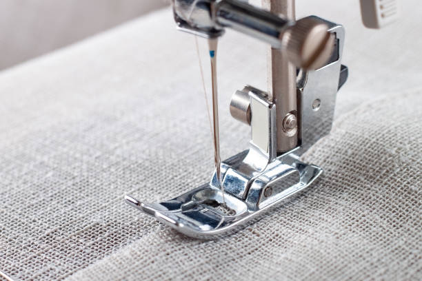 istock Modern sewing machine presser foot with linen fabric and thread, closeup 1477902071