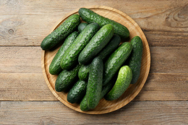 istock Fresh ripe cucumbers on wooden table, top view 1477902072
