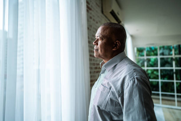 Senior man contemplating while looking through the window at home