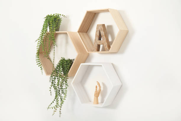 istock Honeycomb shaped shelves with decorative elements and houseplants on white wall 1477905097