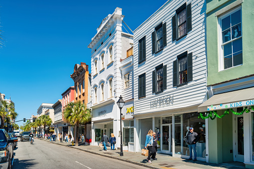 People walk past upscale stores on King Street in downtown Charleston, South Carolina, USA on a sunny day.