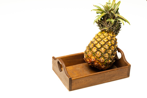 Pineapple fruit in wooden tray over white background.Image made in studio