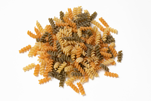 Tricolor fusili pasta on a white background seen from above.