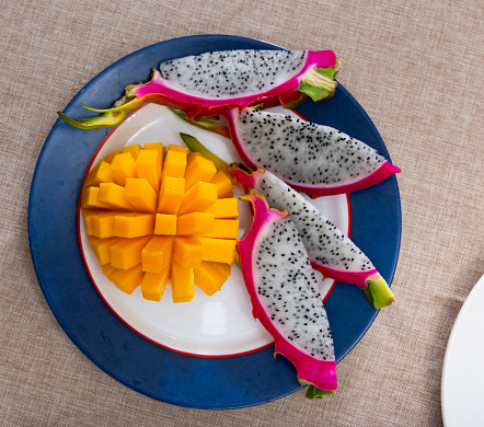 Slices of ripe delicious juicy mango and pitaya on plate. Healthy nutritious tropical fruit dessert