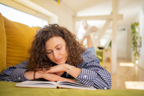 istock Woman reading book at home 1477928474