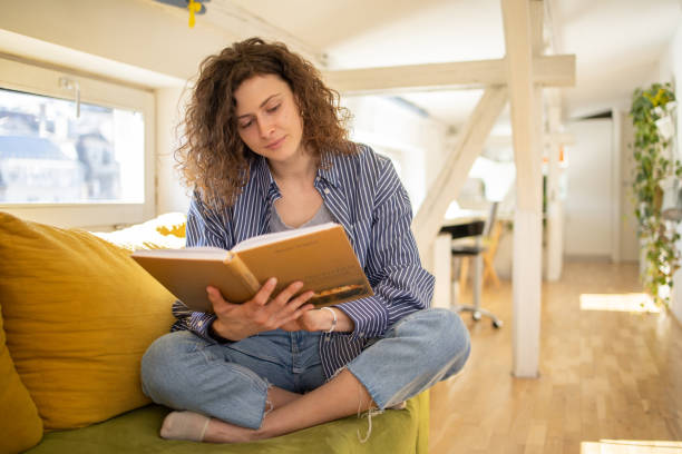 istock Woman reading book at home 1477928478