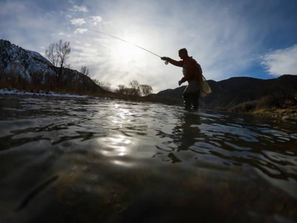 istock Man Fly Fishing Along River Low Angle View 1477931208