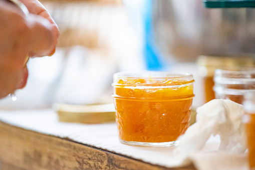 This is a close up of a full jar of homemade mango jam cooling down on a kitchen countertop in Miami, USA.