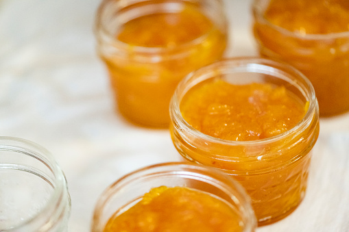 This is a close up of several full jars of homemade mango jam cooling down on a kitchen countertop in Miami, USA.