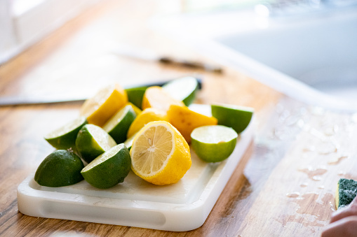 This is a photograph with a shallow depth of field of fresh cut lemons and limes on a cutting board.