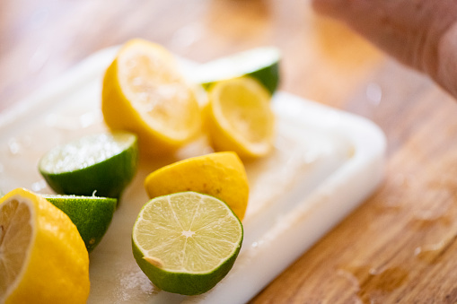 This is a photograph with a shallow depth of field of fresh cut lemons and limes on a cutting board.