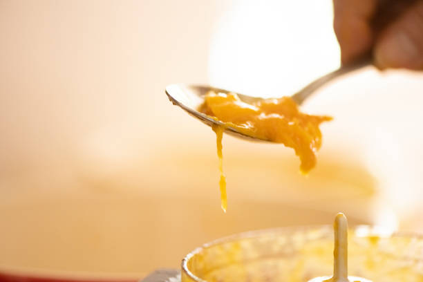 This is a close up of a senior woman’s hand spooning fresh cut homegrown organic mango into the food processor in Miami, USA.
