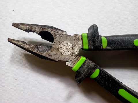 close up photo of green pliers on a white background